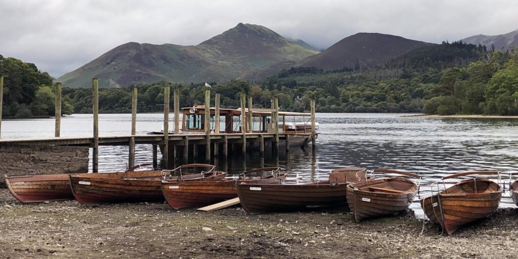 A picture of traditional wooden rowing boats and a steamer on Derwentwater by Keswick